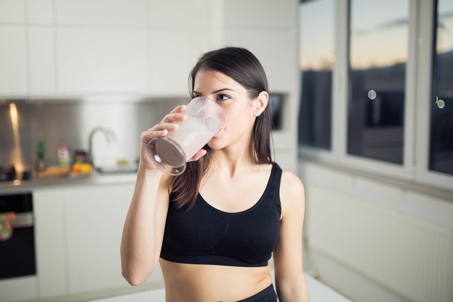 Woman drinking banana chocolate protein powder milkshake smoothi